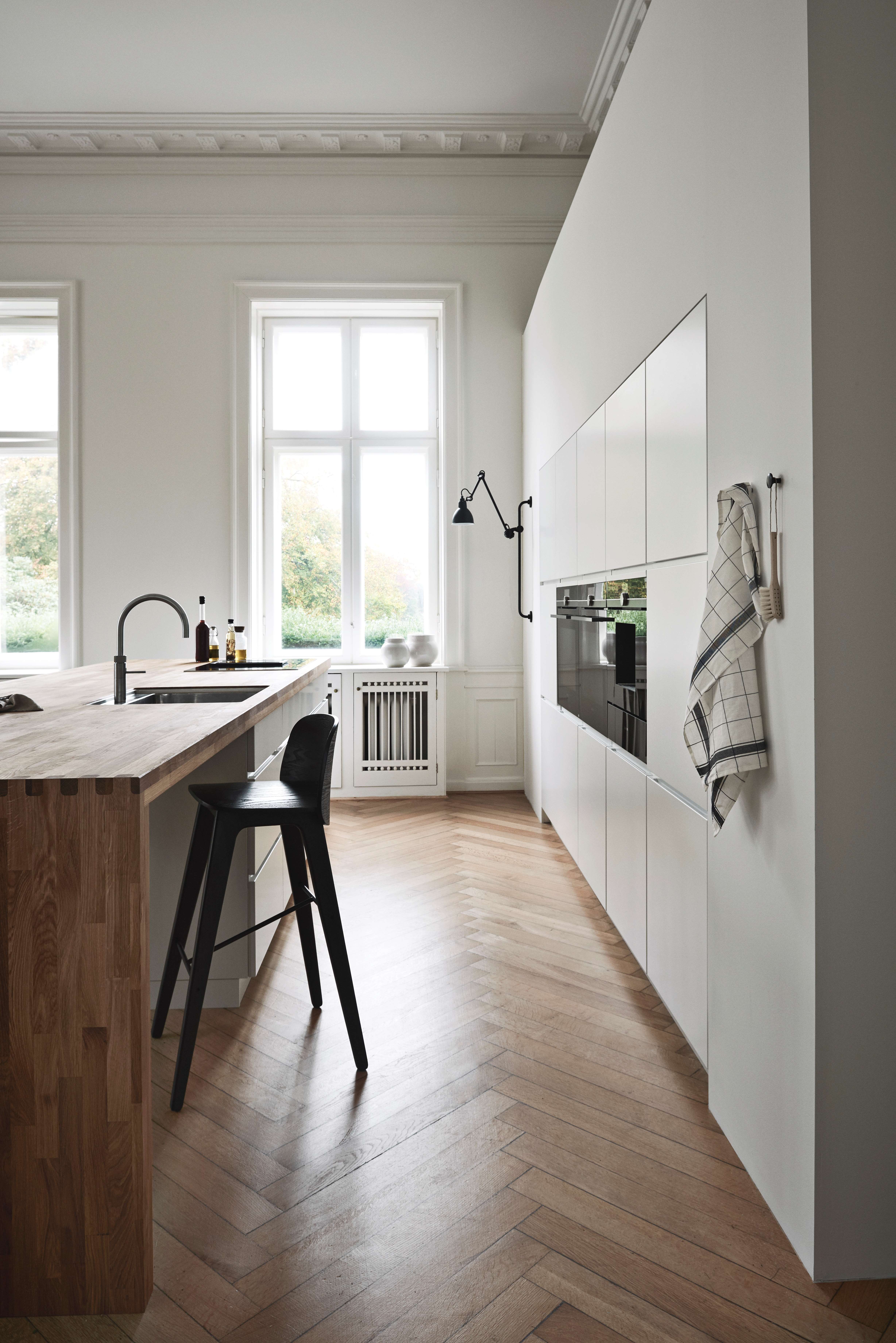 Weisse Küche mit eingebauten Öfen und einer Arbeitsplatte aus Massivholz