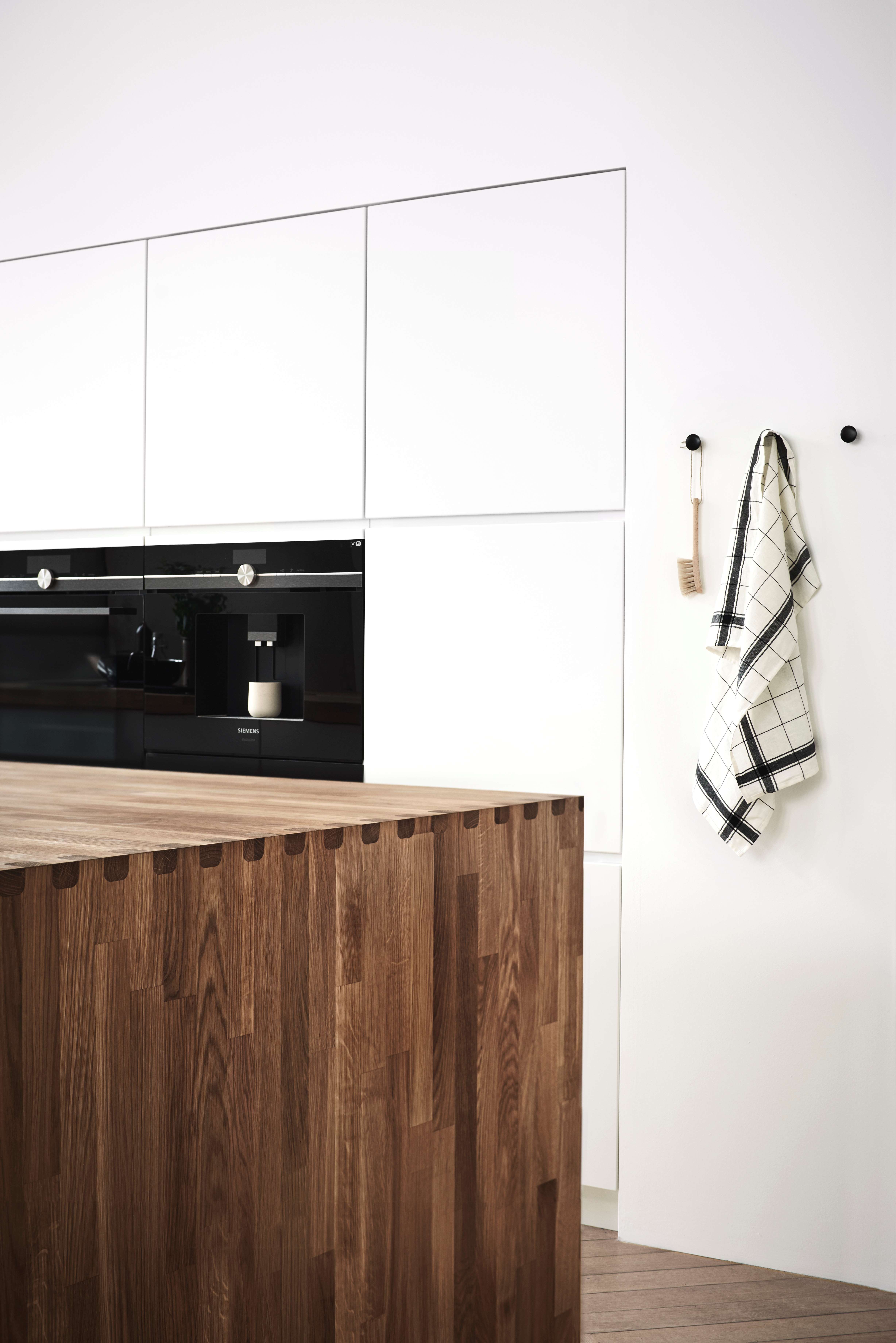 Witte keuken met ingebouwde ovens en een massief houten werkblad
