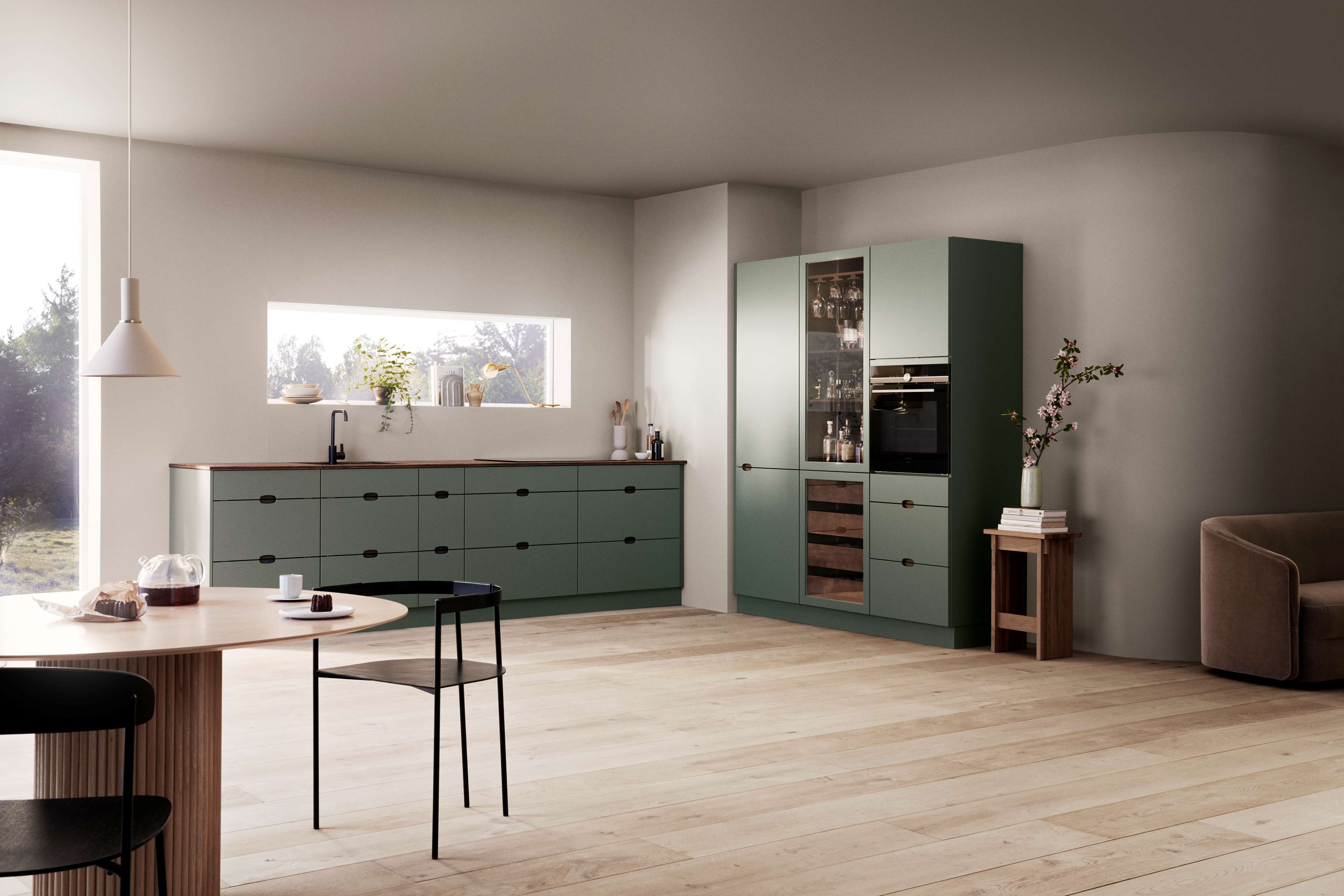 Green kitchen with a wine refrigerator and a wooden worktop