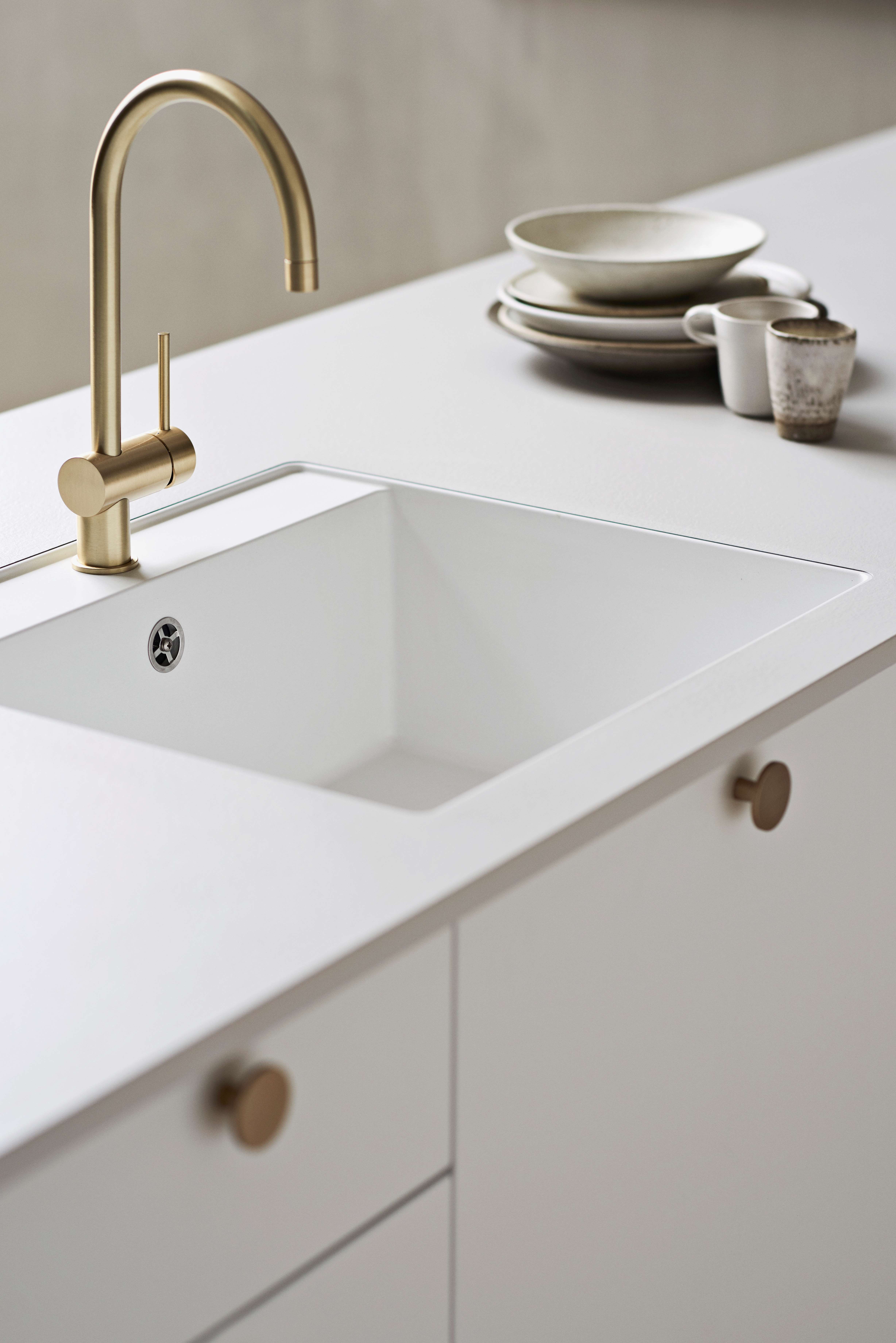 White kitchen with dot handles and a golden faucet