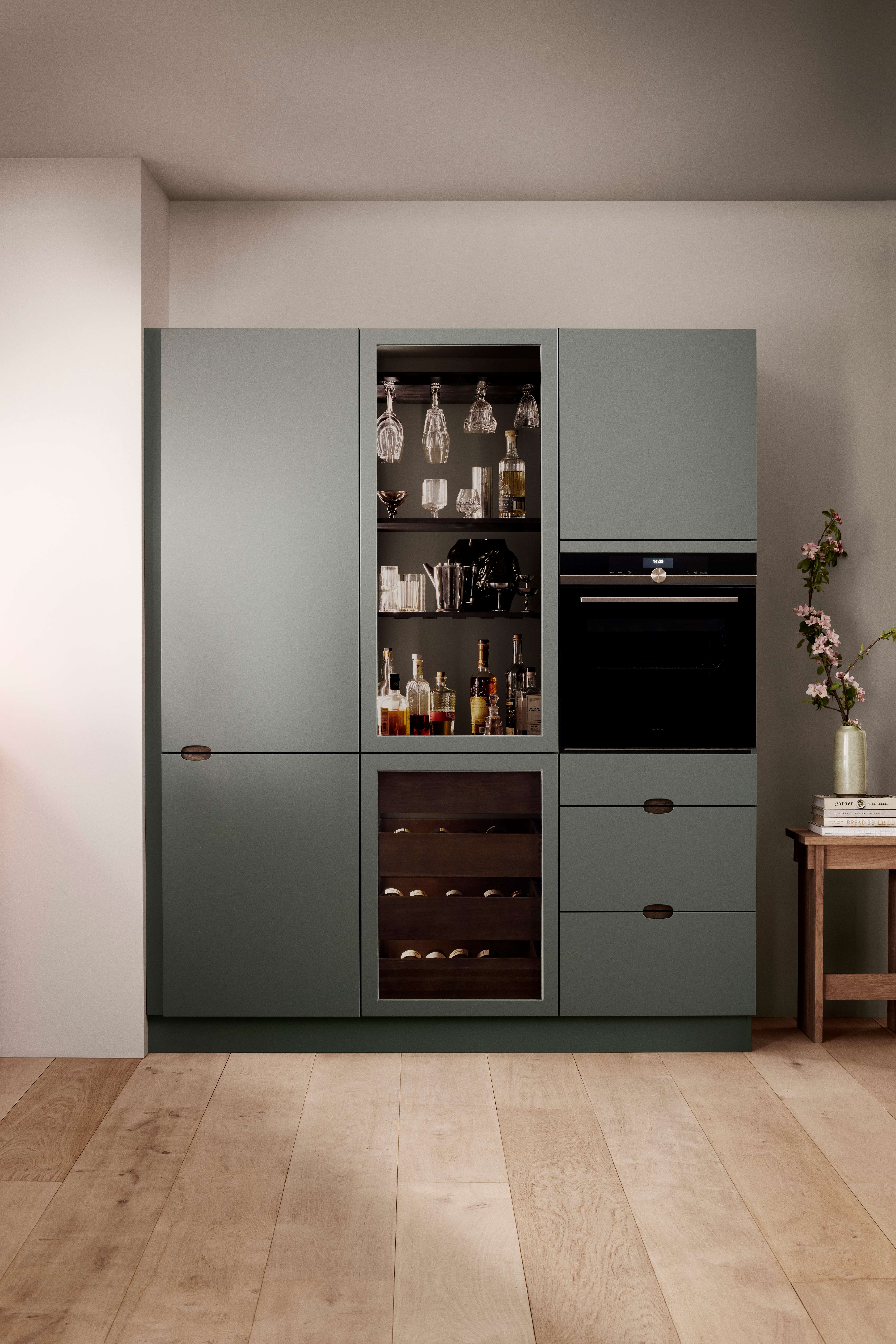 Green kitchen cabinet with an integrated oven and wine refrigerator