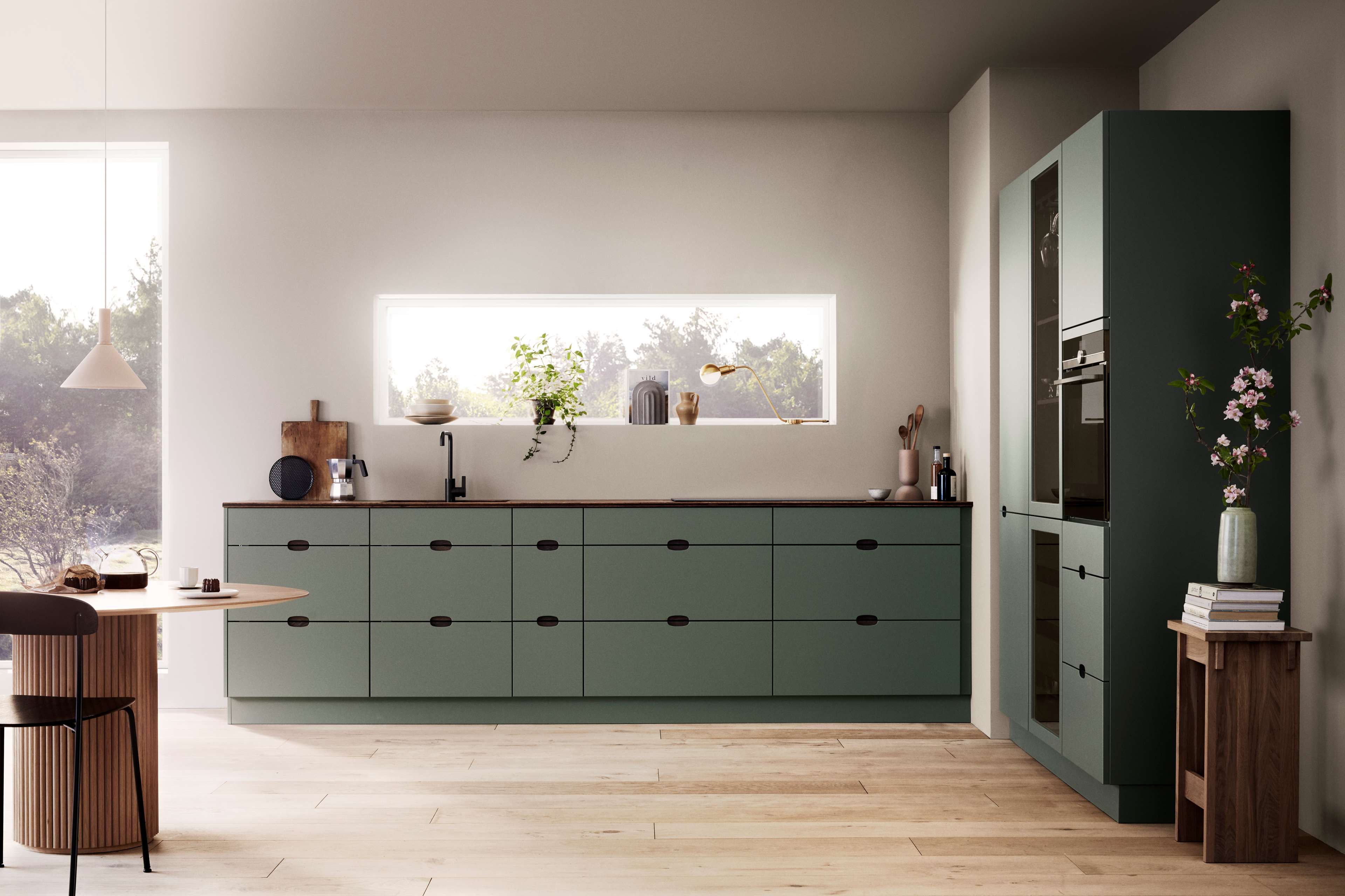Green kitchen with integrated handles and a wooden worktop