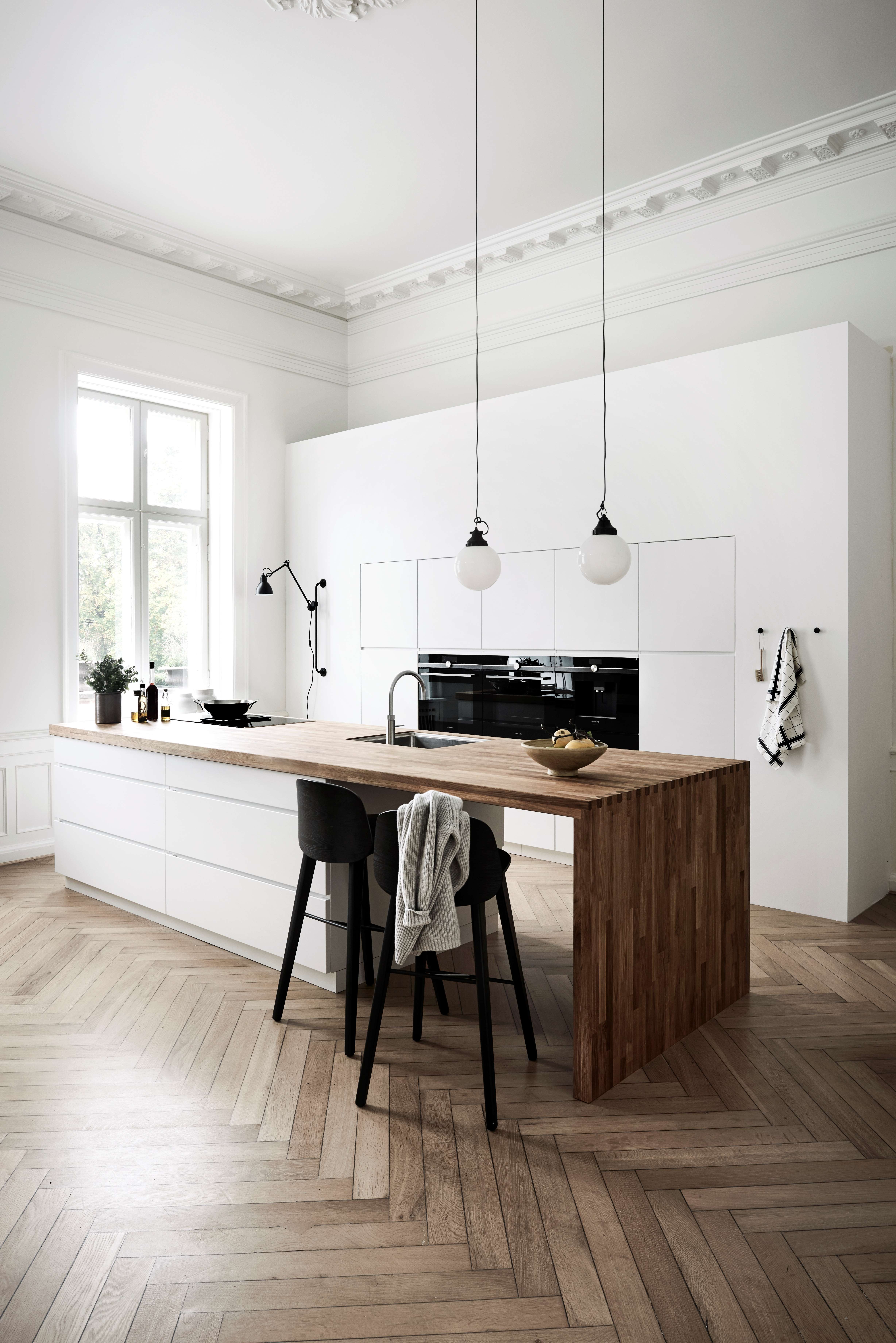 Hvitt kjøkken med kjøkkenøy og en arbeidsbenk av massivt tre