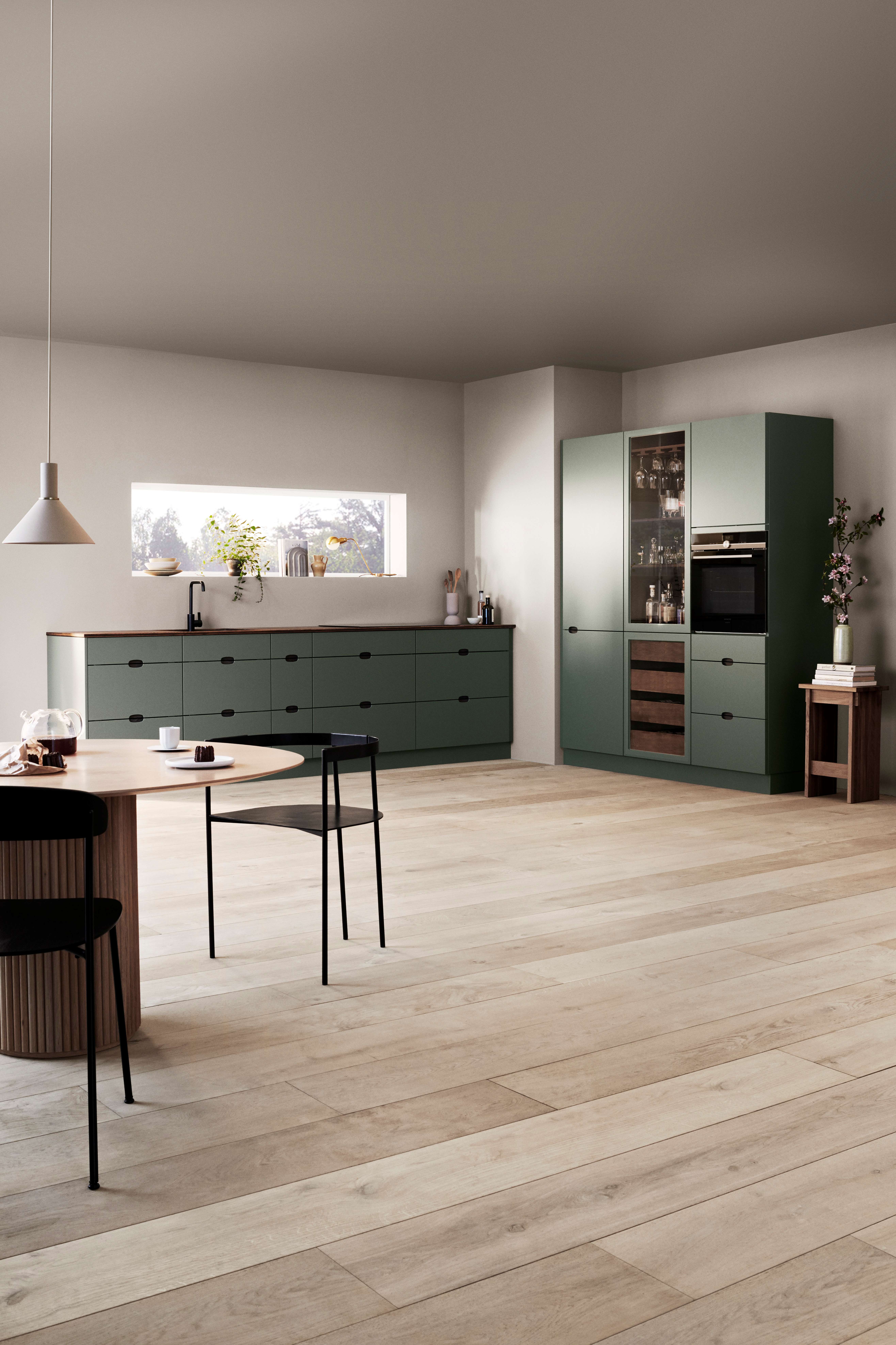 Green kitchen with a wine refrigerator and a wooden worktop