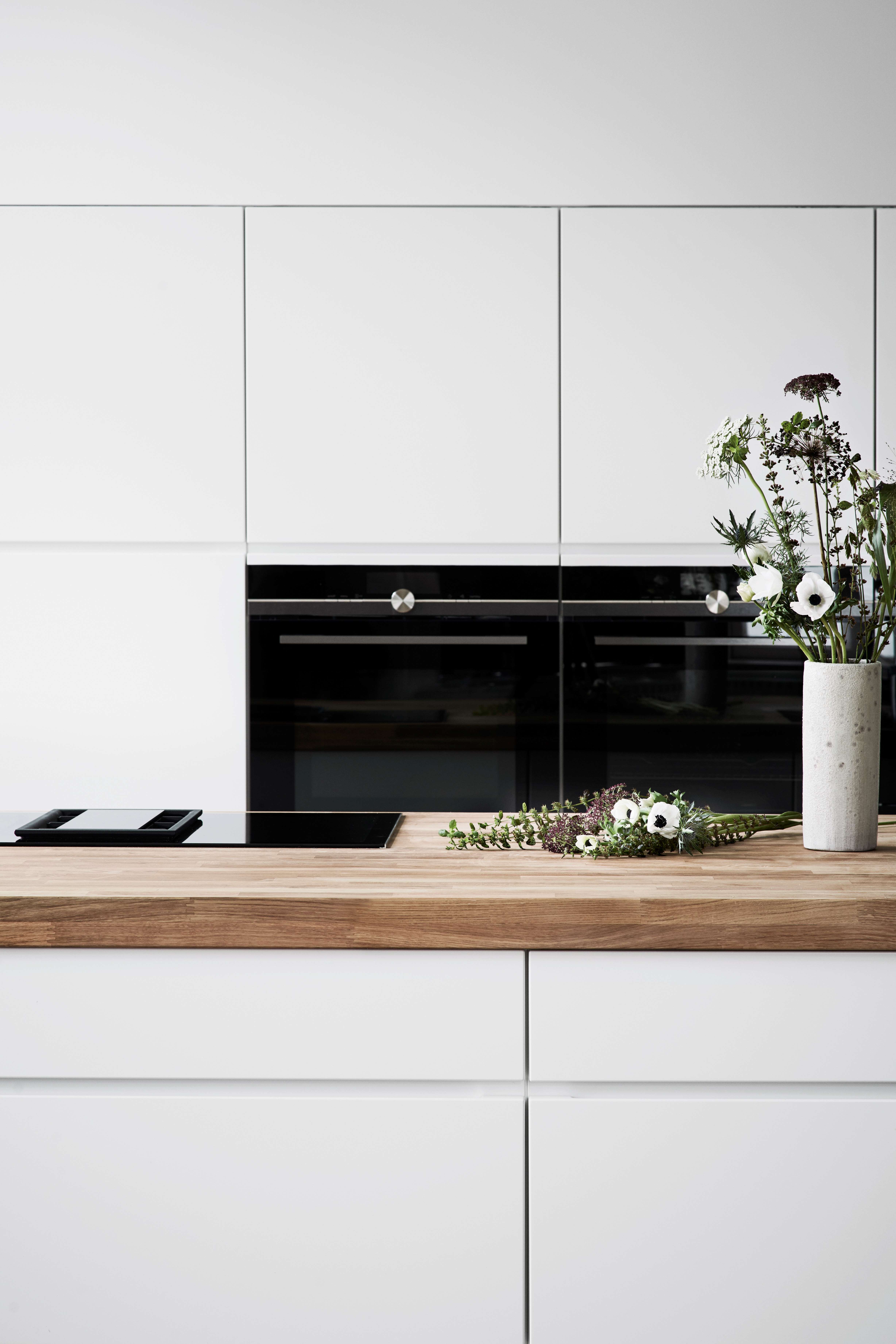 Hvitt kjøkken med massivt trebenkeplate og innebygde hvitevarer